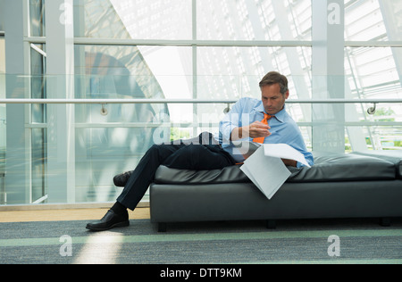 Caucasian businessman reading in lobby area Stock Photo