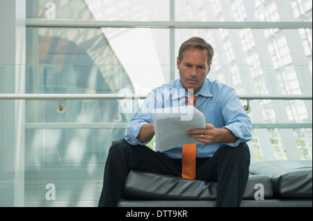 Caucasian businessman reading in lobby area Stock Photo