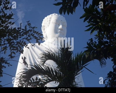 Giant white Buddha on hilltop and framed by trees at Long Son Temple in Nha Trang, Khanh Hoa province, Vietnam Stock Photo