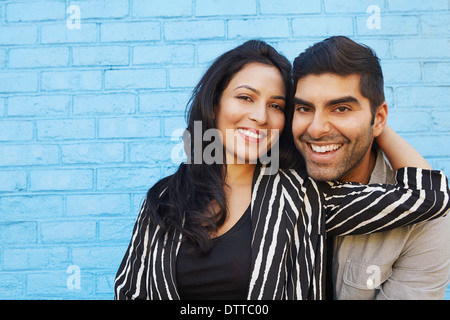 Indian couple hugging along blue brick wall Stock Photo