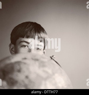 Boy peering over globe Stock Photo