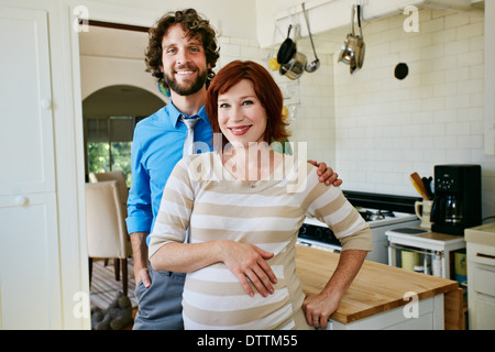 Pregnant Caucasian couple smiling in kitchen Stock Photo