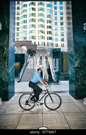 Caucasian businessman riding bicycle outside highrise Stock Photo