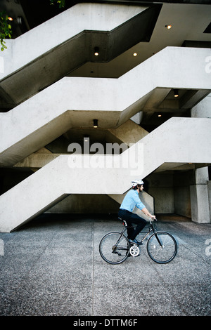 Caucasian businessman riding bicycle outside office building Stock Photo