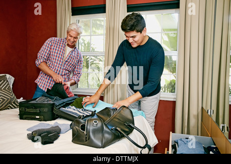 Homosexual couple packing suitcases in bedroom Stock Photo