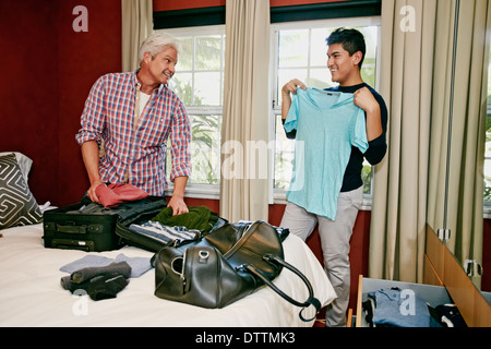 Homosexual couple packing suitcases in bedroom Stock Photo