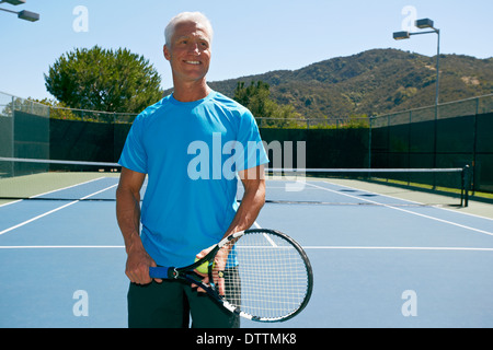 Caucasian man smiling on tennis court Stock Photo