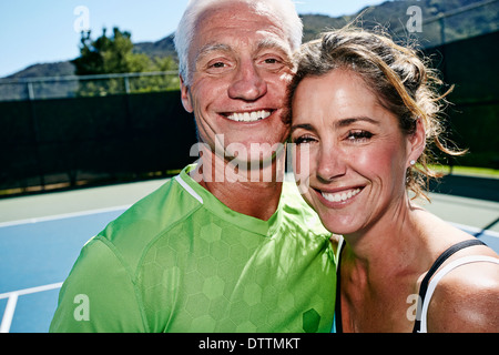 Caucasian couple hugging on tennis court Stock Photo