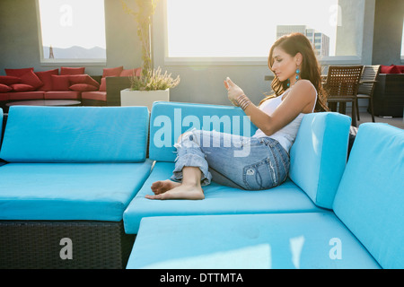 Middle Eastern woman using cell phone on sofa Stock Photo