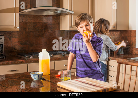 Boy eating fruit in kitchen Stock Photo