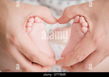 Close up of Hispanic mother cupping baby boy's feet Stock Photo