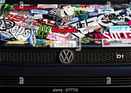 VW badge on front grille of Volkswagen vehicle covered in stickers Stock Photo