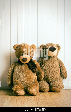 two teddy bears in front of an old wooden wall Stock Photo