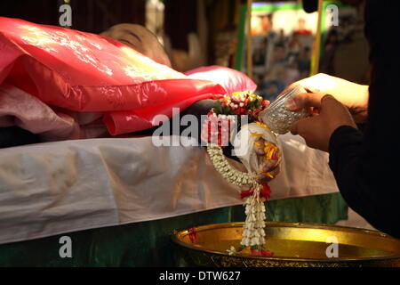 Bangkok, Thailand. 24th Feb, 2014. People pours water on the hands of the body of 6-year-old Patcharakorn Yosubon the victim of a bomb blast, during the last rites performed at a Buddhist Temple. Two young siblings, 6-year-old girl Patcharakorn and her 4-year-old brother Korawit, along with another woman were killed wounding at least 22 people in an grenade attack against anti-government protesters in shopping district in Bangkok. Credit:  John Vincent/Alamy Live News Stock Photo