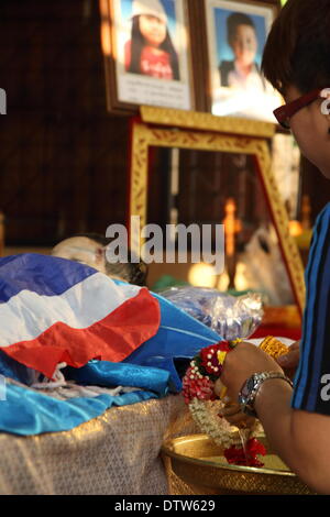 Bangkok, Thailand. 24th Feb, 2014. People pours water on the hands of the body of 4-year-old Korawit Yosubon the victim of a bomb blast, during the last rites performed at a Buddhist Temple. Two young siblings, 6-year-old girl Patcharakorn and her 4-year-old brother Korawit, along with another woman were killed wounding at least 22 people in an grenade attack against anti-government protesters in shopping district in Bangkok. Credit:  John Vincent/Alamy Live News Stock Photo