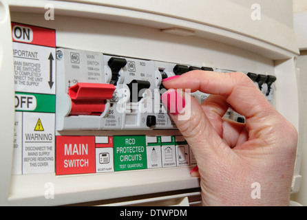 Woman switches trip/residual current device (RCD) / consumer unit in a domestic setting/home Stock Photo