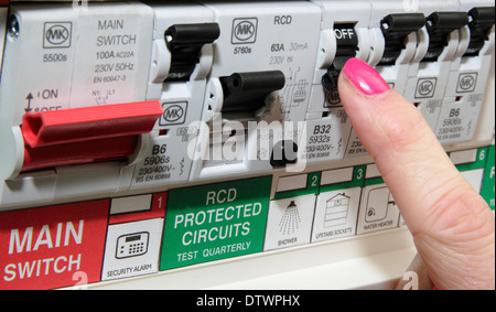 Woman switches trip/residual current device (RCD) / consumer unit in a domestic setting/home Stock Photo