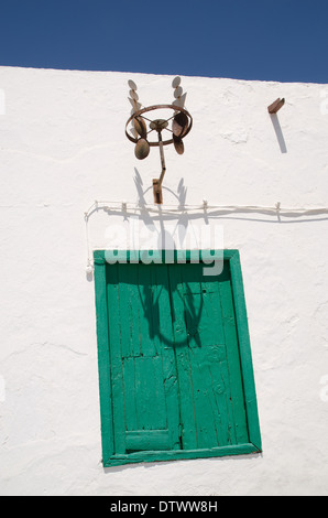 Old Green painted door in white wall with shadow of metal sculpture Stock Photo