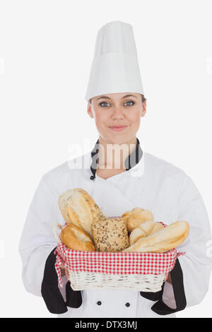 Female chef in uniform holding bread basket Stock Photo