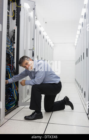 Technician kneeling and repairing a server Stock Photo