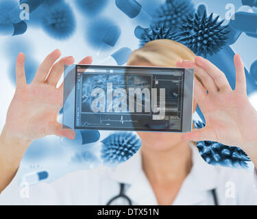 Happy blonde nurse holding a virtual screen Stock Photo