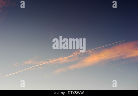 Jet contrails and pink clouds against blue sunset sky in Colorado, USA Stock Photo