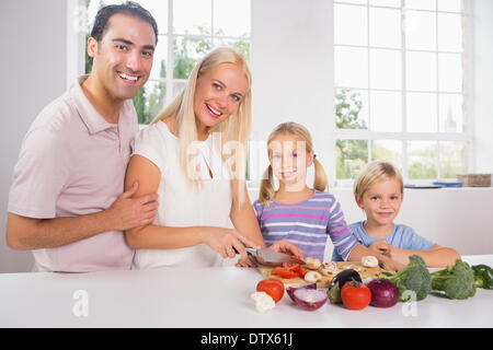 Smiling family cutting vegetables together Stock Photo