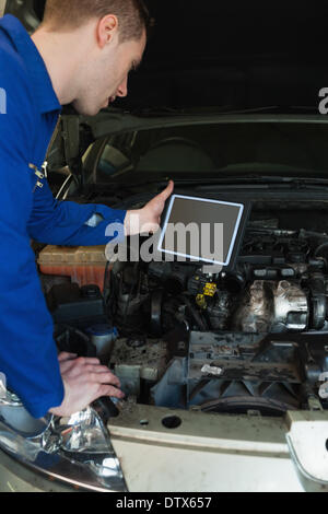 Mechanic by car holding tablet pc Stock Photo