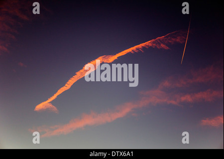 Jet contrails and pink clouds against blue sunset sky in Colorado, USA Stock Photo
