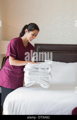 Hotel maid putting towels on bed Stock Photo