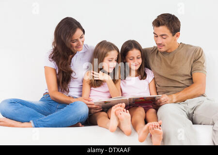 Family reading a story on a sofa Stock Photo