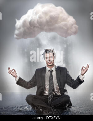 Businessman meditating under cloud Stock Photo