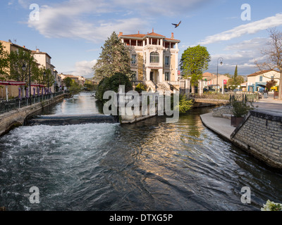 At the confluence a duck takes off. At the joining of two of the many streams in this small Provençal town stands a mansion Stock Photo