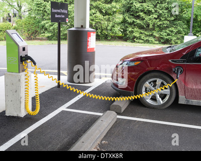 Reserved for Charging an Electric Car. A plug-in Chevrolet Volt car plugged into a parking-lot charging station. Stock Photo