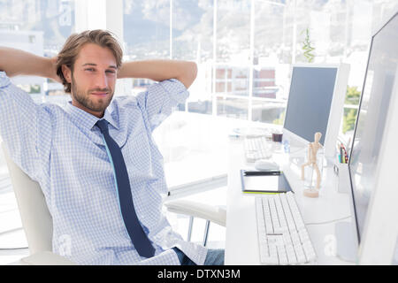 Smiling designer with arms behind head Stock Photo