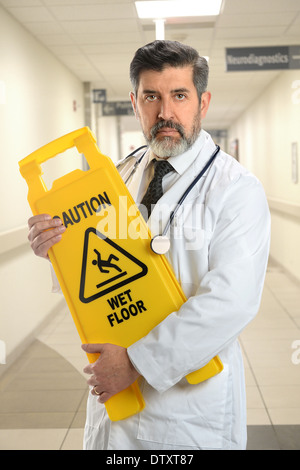 Portrait of senior Hispanic doctor holding caution sign inside hospital Stock Photo