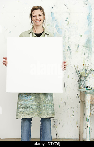 Caucasian painter holding blank canvas in studio Stock Photo
