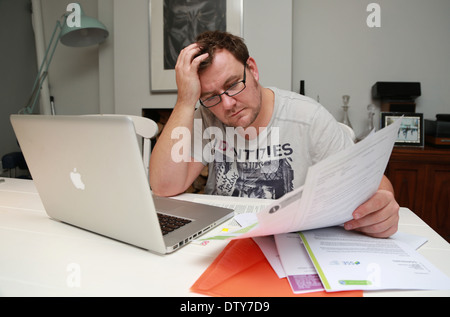 Man using a laptop and doing paperwork. Stock Photo