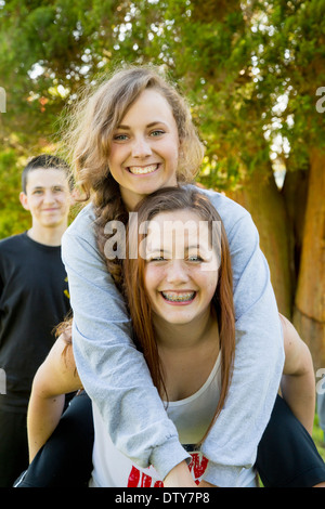 Caucasian teenage girls piggybacking outdoors Stock Photo