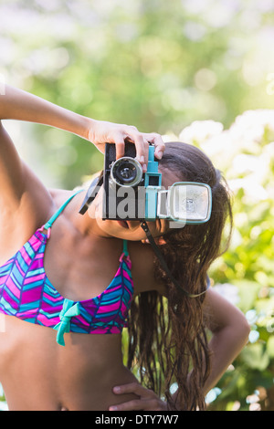 Mixed race girl taking pictures with toy camera outdoors Stock Photo