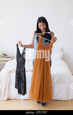Chinese woman picking out dresses in bedroom Stock Photo