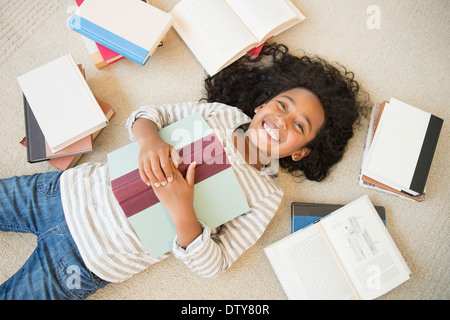 Mixed race girl laying on floor with books Stock Photo