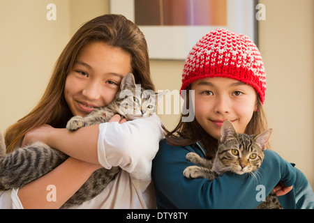 Mixed race girls holding kittens Stock Photo