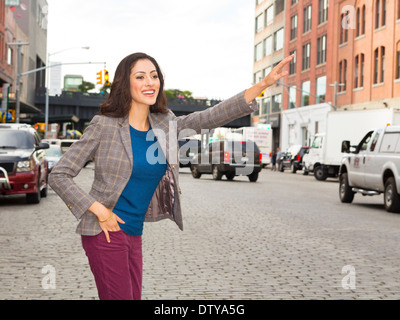 Mixed race woman hailing taxi on city street Stock Photo