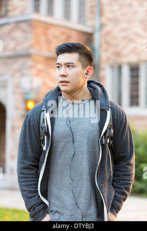 Mixed race college student listening to music on headphones Stock Photo