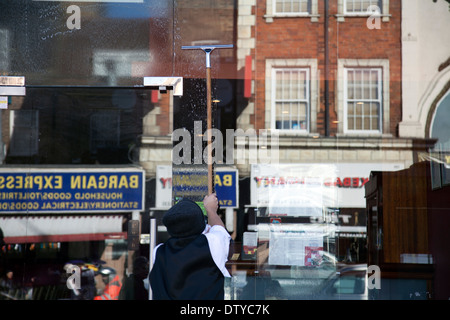 Man Washing Windows to Indian Restaurant in Clapham - London UK Stock Photo