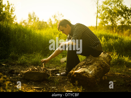 Caucasian man lighting campfire in rural field Stock Photo