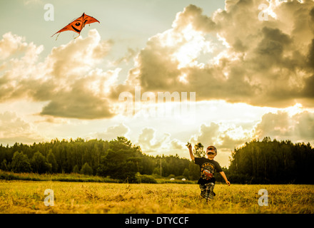 Caucasian boy flying kite in rural field Stock Photo