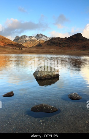 Rocks in the foreground, and the Langdale Pikes are reflected in the waters of Blea Tarn, Lake District National Park, England