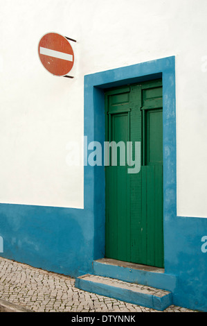 Old green door set in a blue and white wall with a red no entry street sign, Portugal Stock Photo